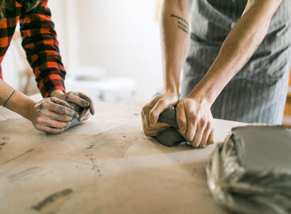 Two potters wedging clay in preperation for throwing