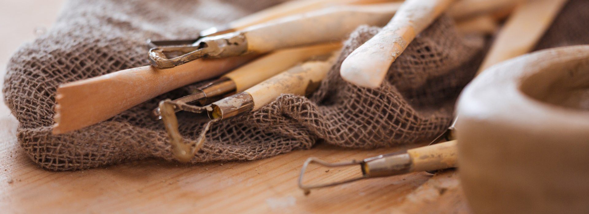 Set of dirty art and craft sculpting tools on wooden table in pottery workshop